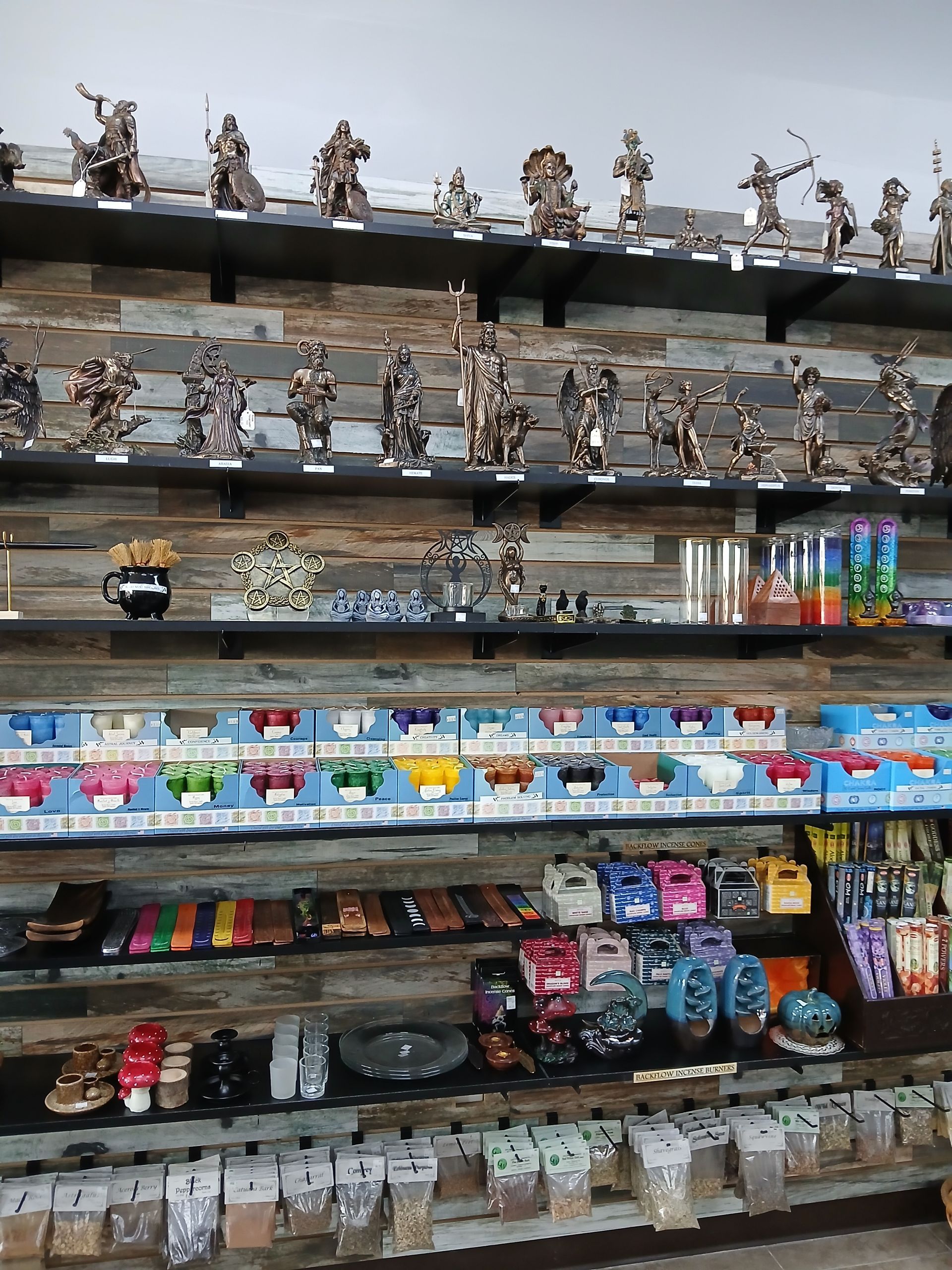 Shelves stocked with various figurines, incense, and related items in a retail setting.