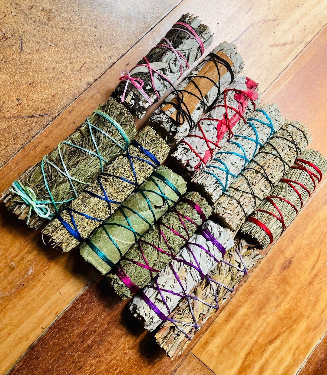 Bundles of dried herbs wrapped with colorful twine on a wooden surface.