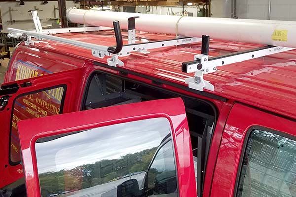 A red van with a ladder rack on top of it.