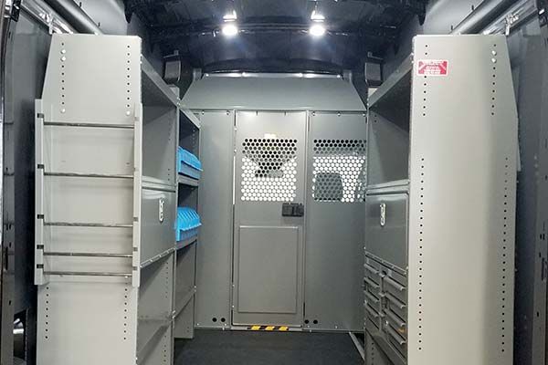 The inside of a van with steel shelves and drawers.