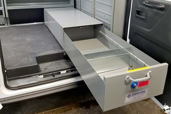 A drawer is open in the back of a van.