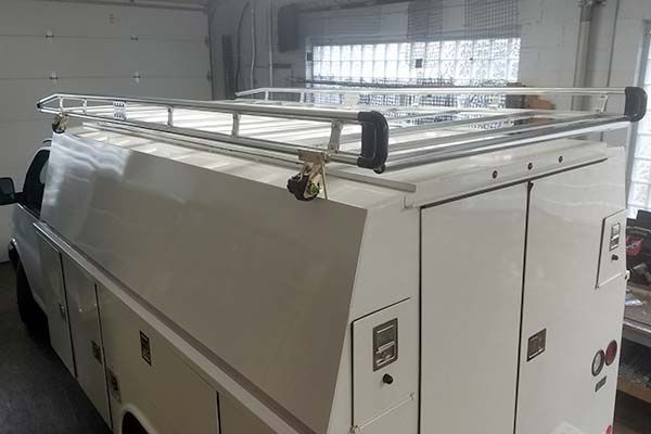 A white van with a roof rack is parked in a garage.