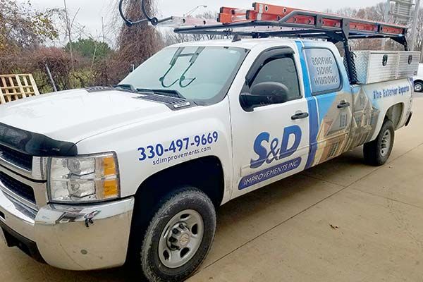 A white s & d truck is parked on the side of the road.