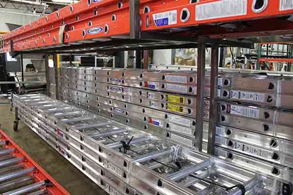 A row of ladders stacked on top of each other in a warehouse.
