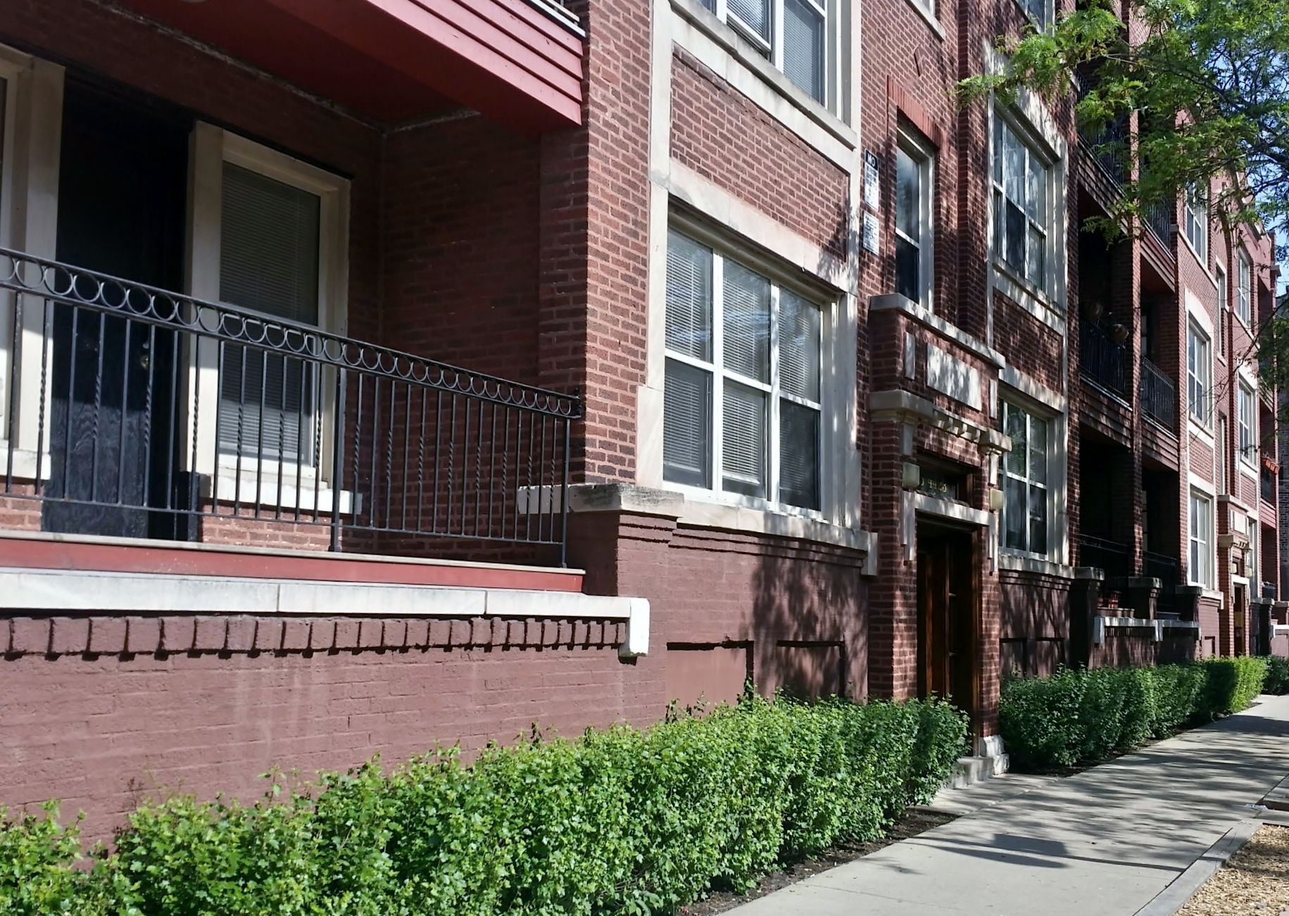 A brick apartment building with a balcony and a sidewalk