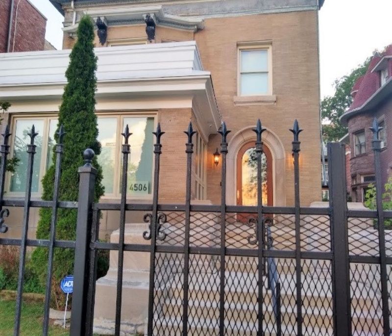 A brick house with a wrought iron fence around it