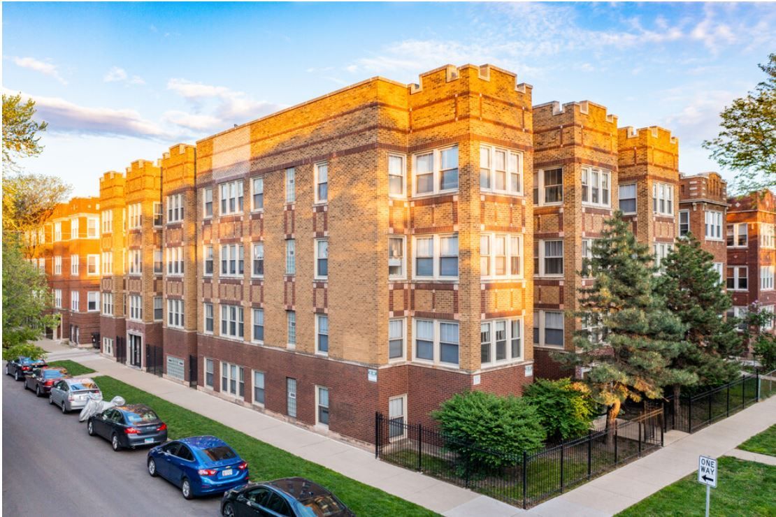A large brick apartment building with cars parked in front of it.