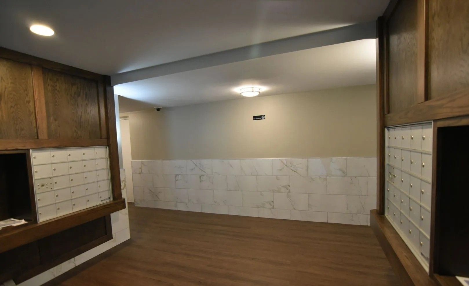 An empty room with a wooden floor and a marble wall.