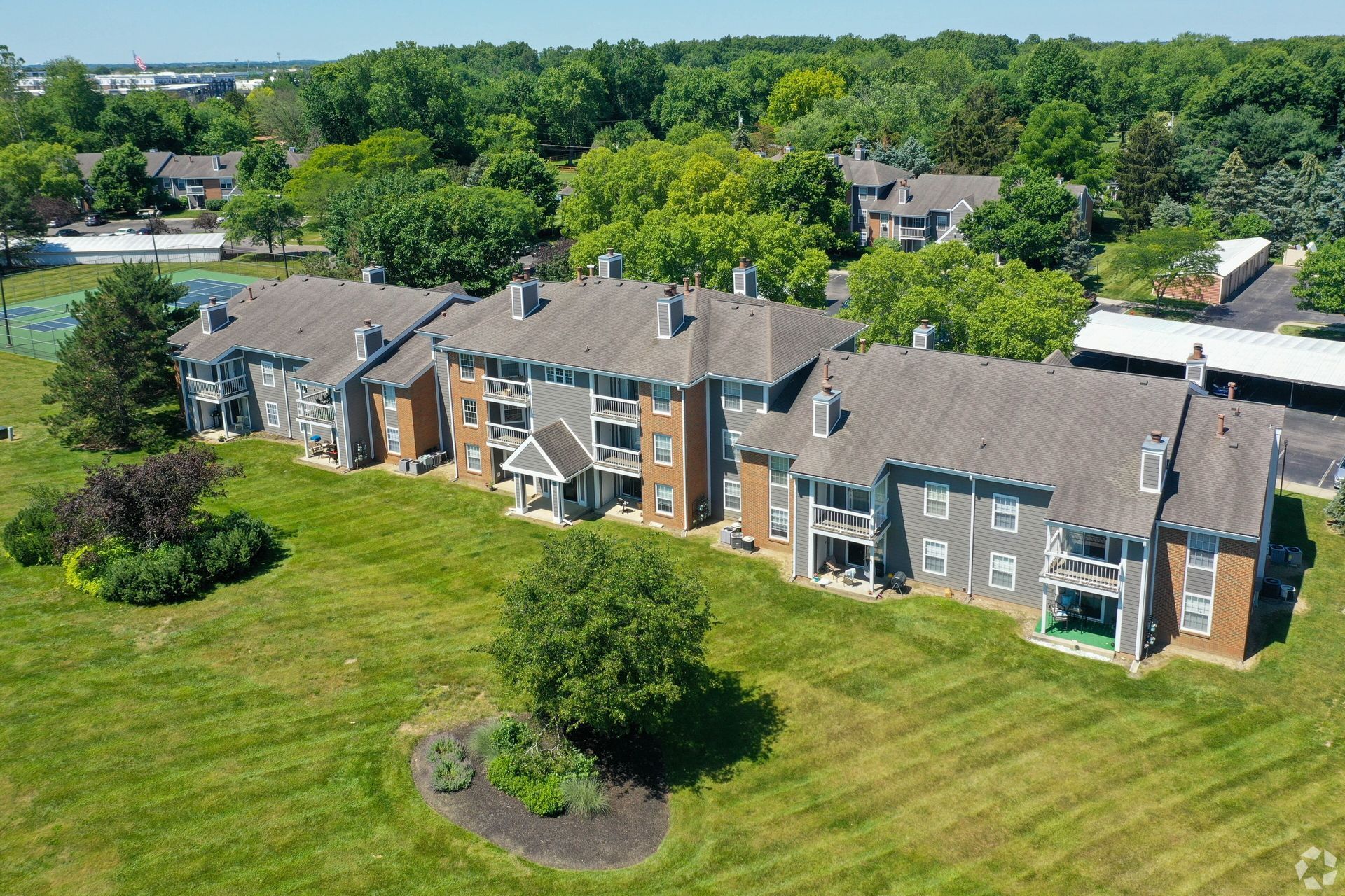 An aerial view of a row of apartment buildings surrounded by trees.- Click to go to Ohio Properties
