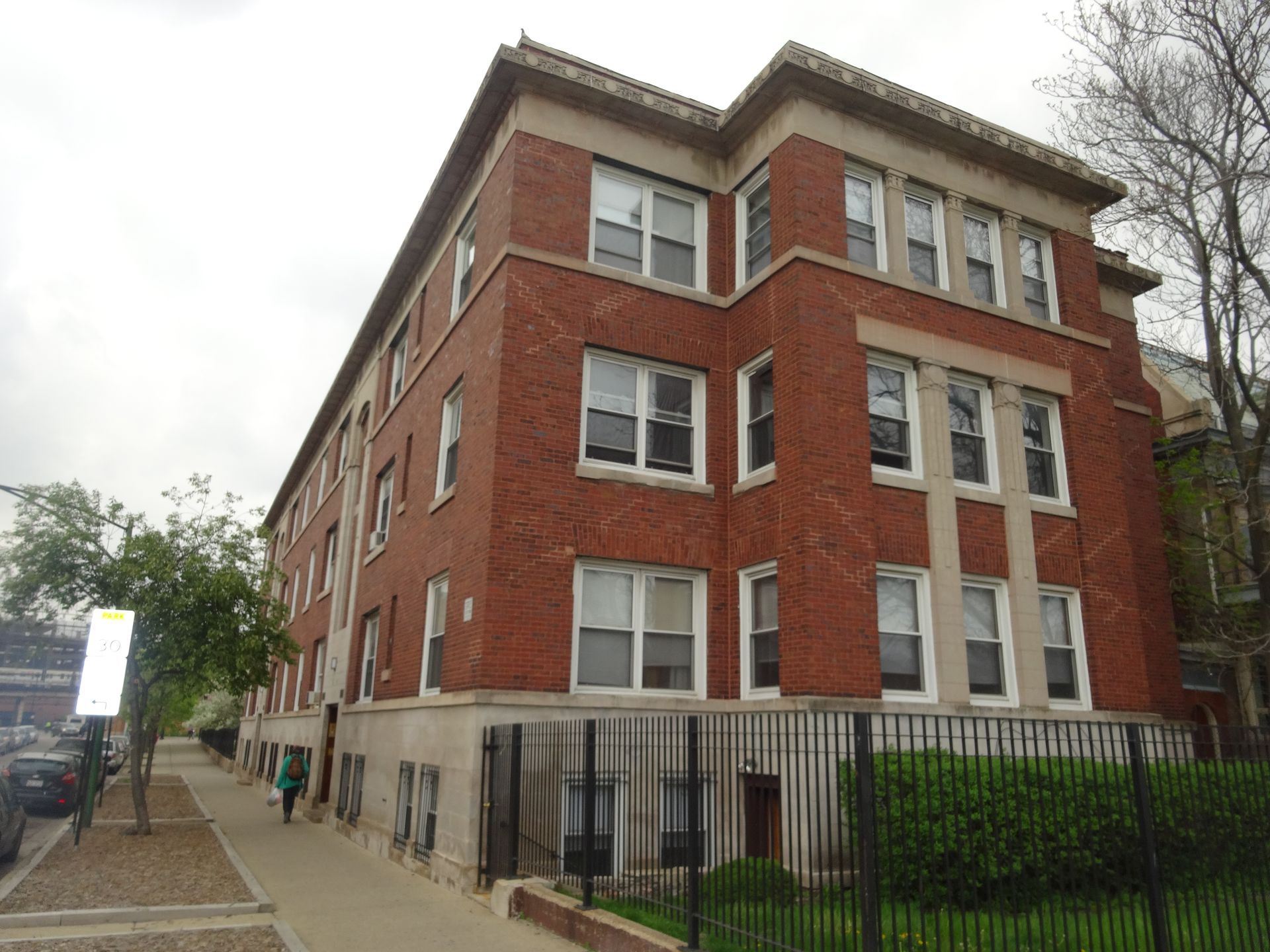 A large brick building with a lot of windows and a fence around it
