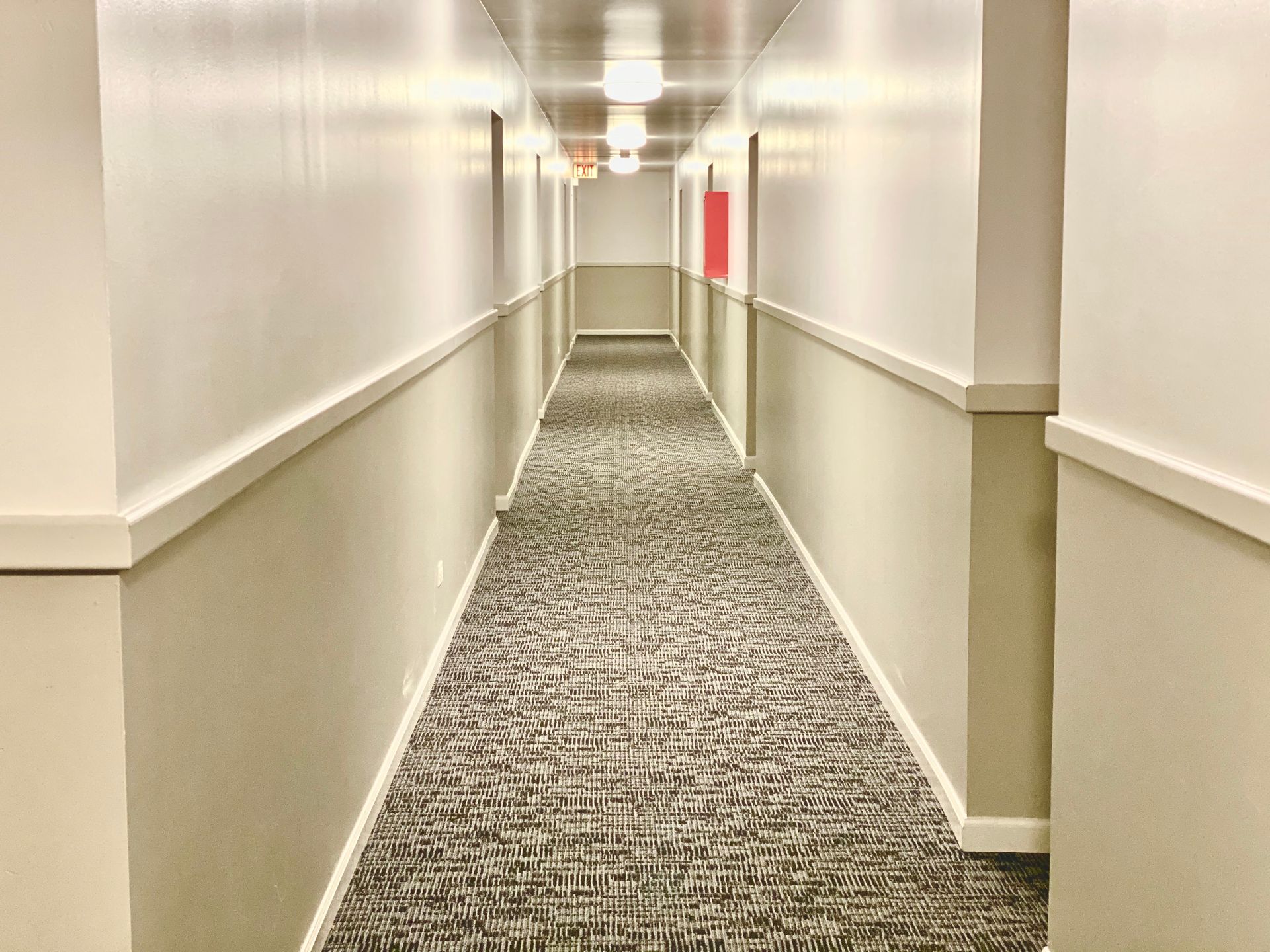 A long hallway with a carpeted floor and white walls.