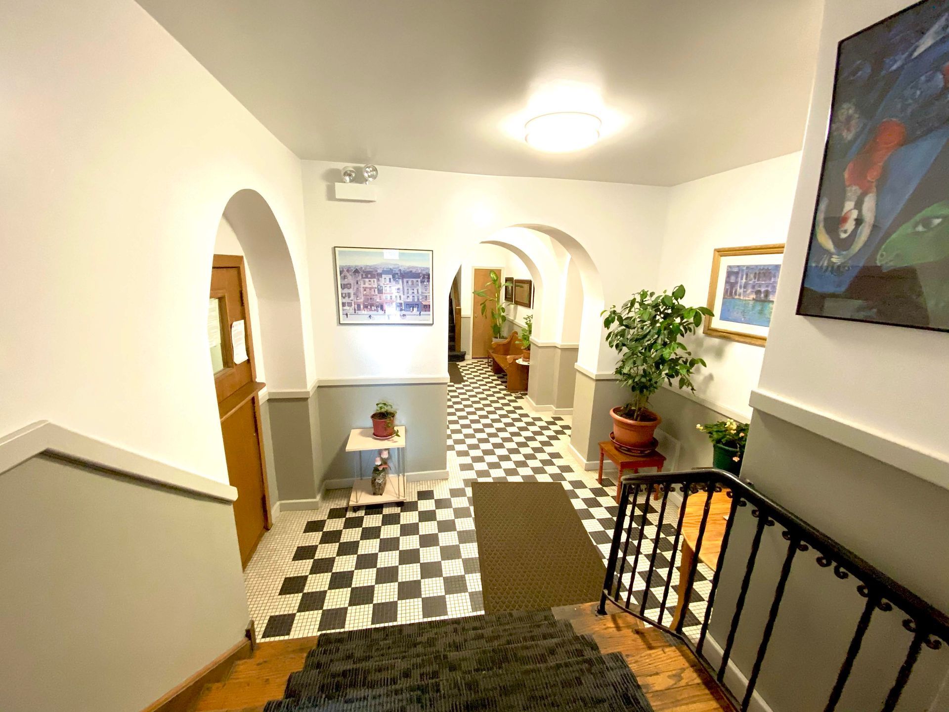 A hallway with stairs and a checkered floor