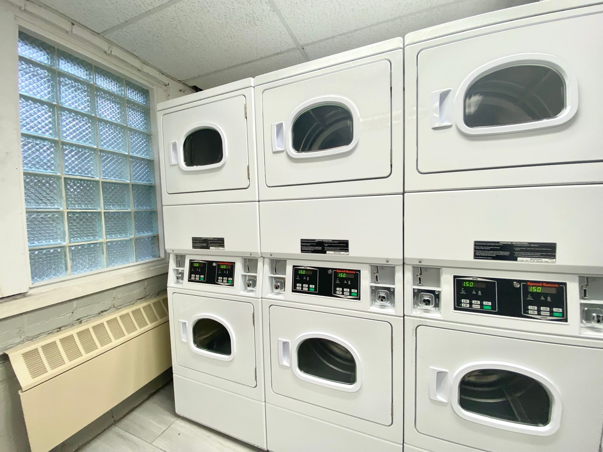A laundromat with a lot of washers and dryers stacked on top of each other.
