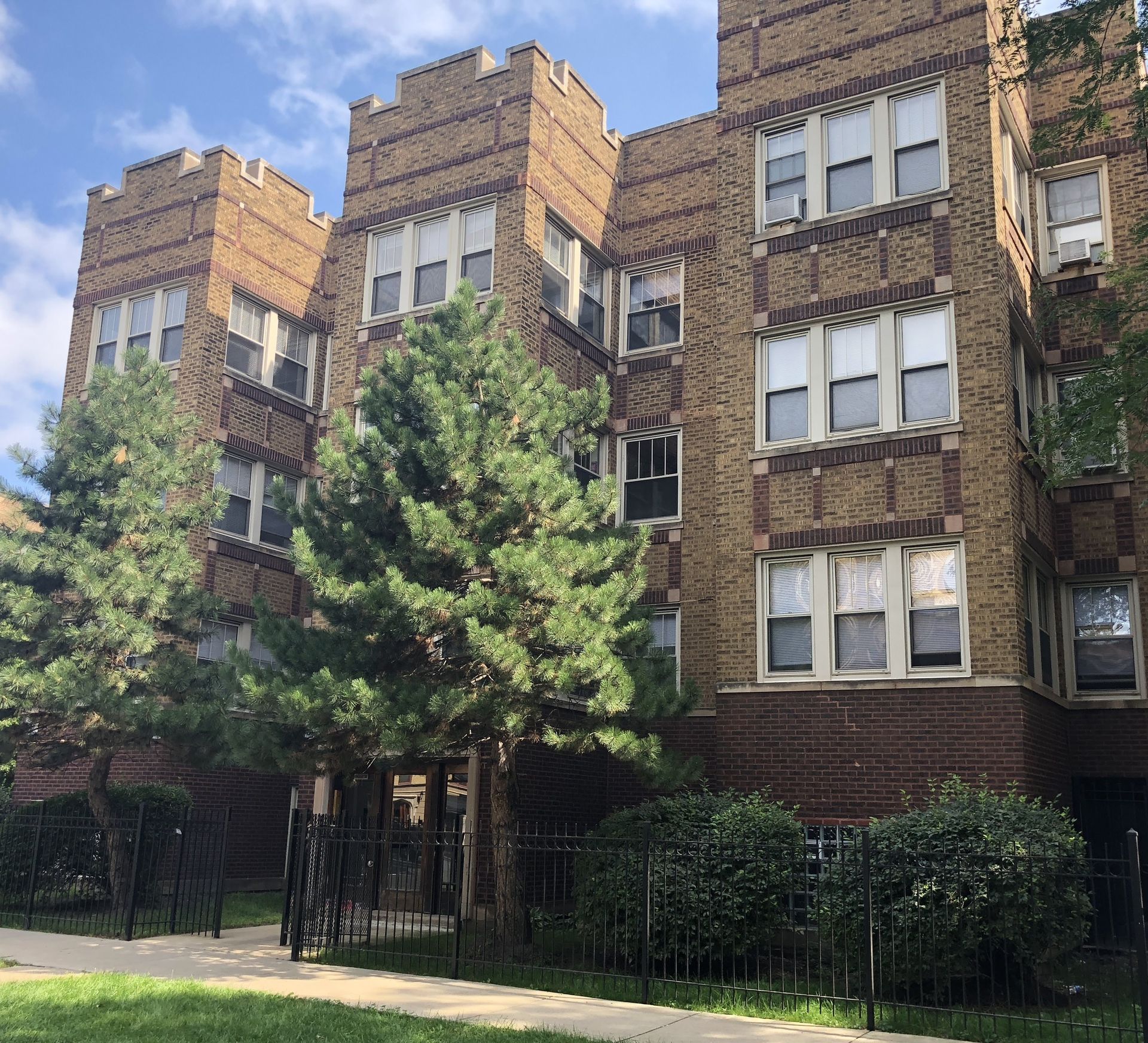 A large brick building with a lot of windows and trees in front of it.
