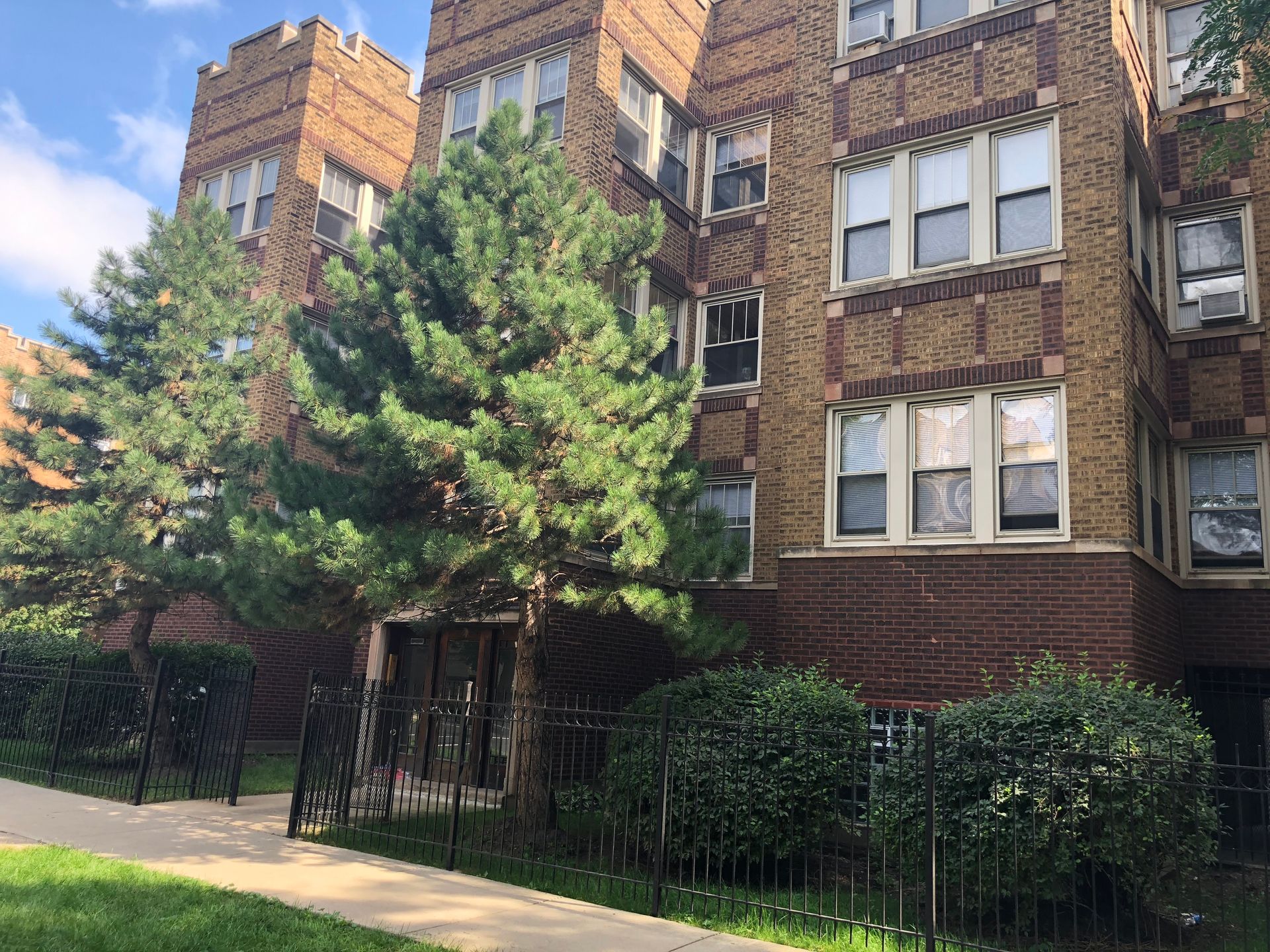 A large brick building with a lot of windows and trees in front of it.