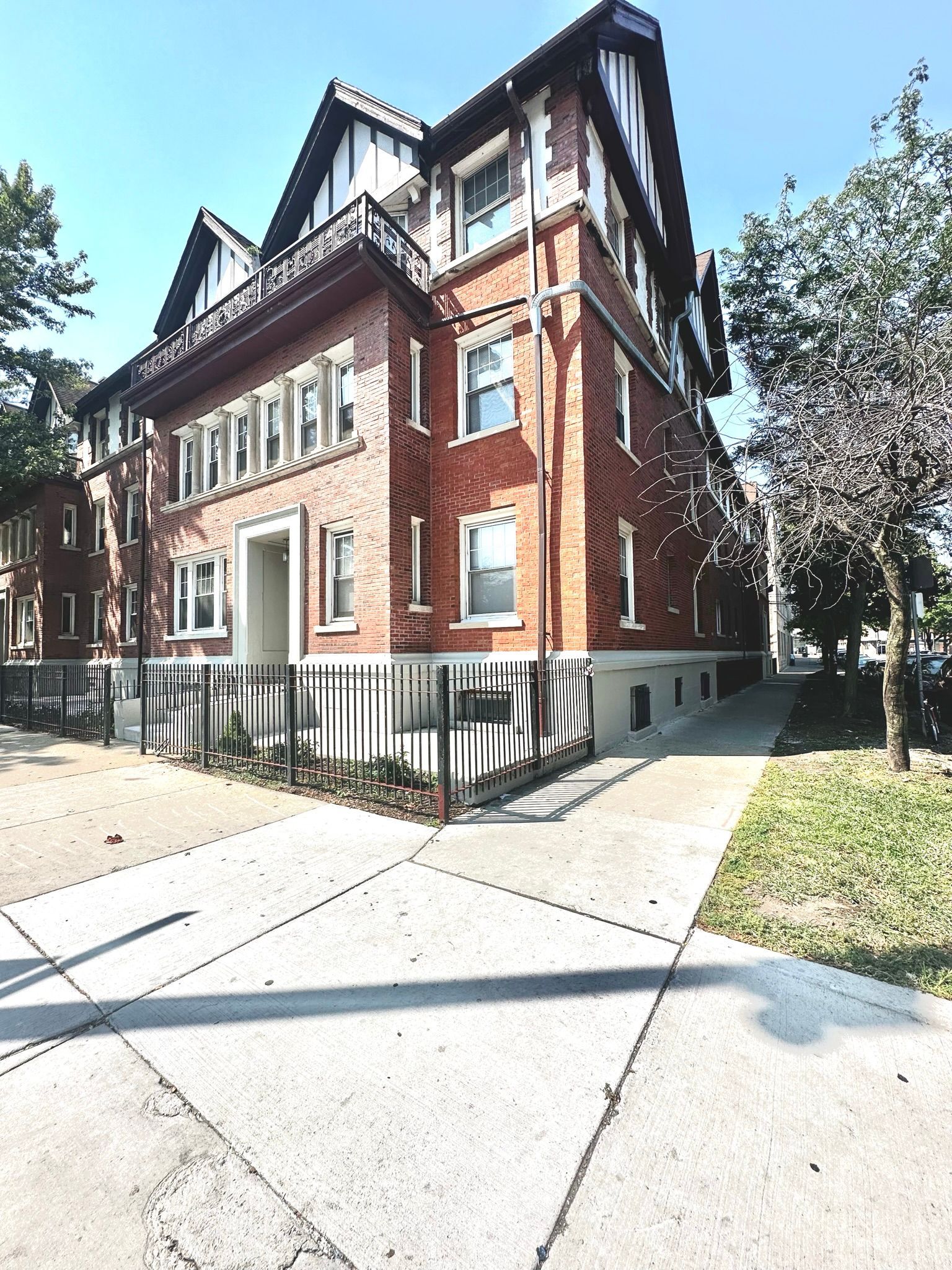 A large brick building is on the corner of a street.