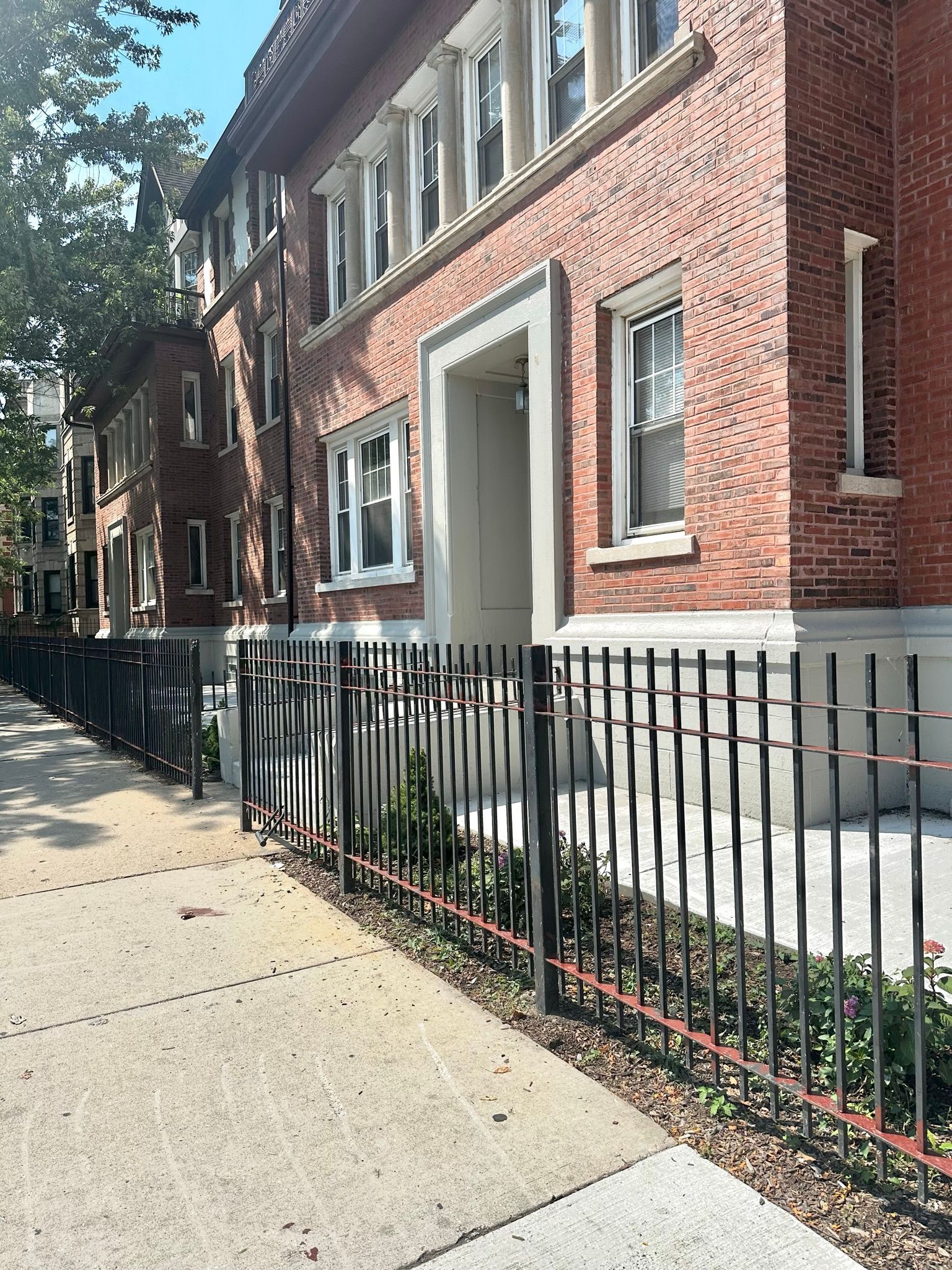 A brick building with a wrought iron fence around it.