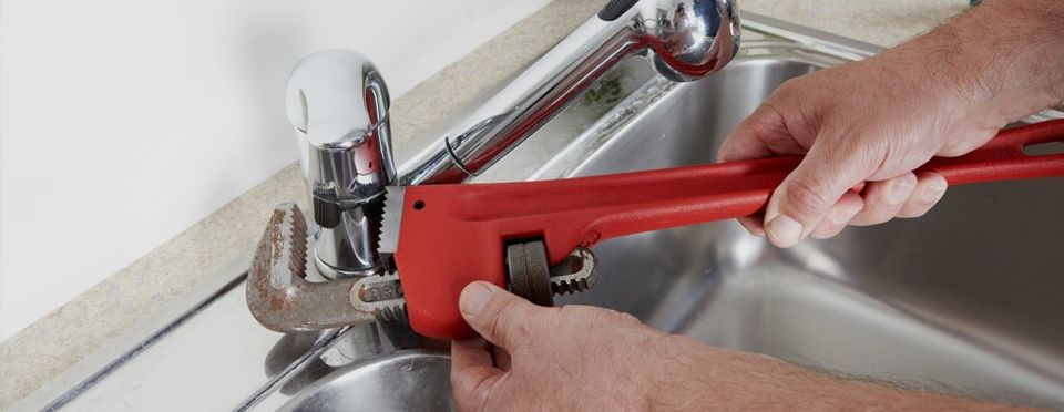 A plumber using a wrench on a tap