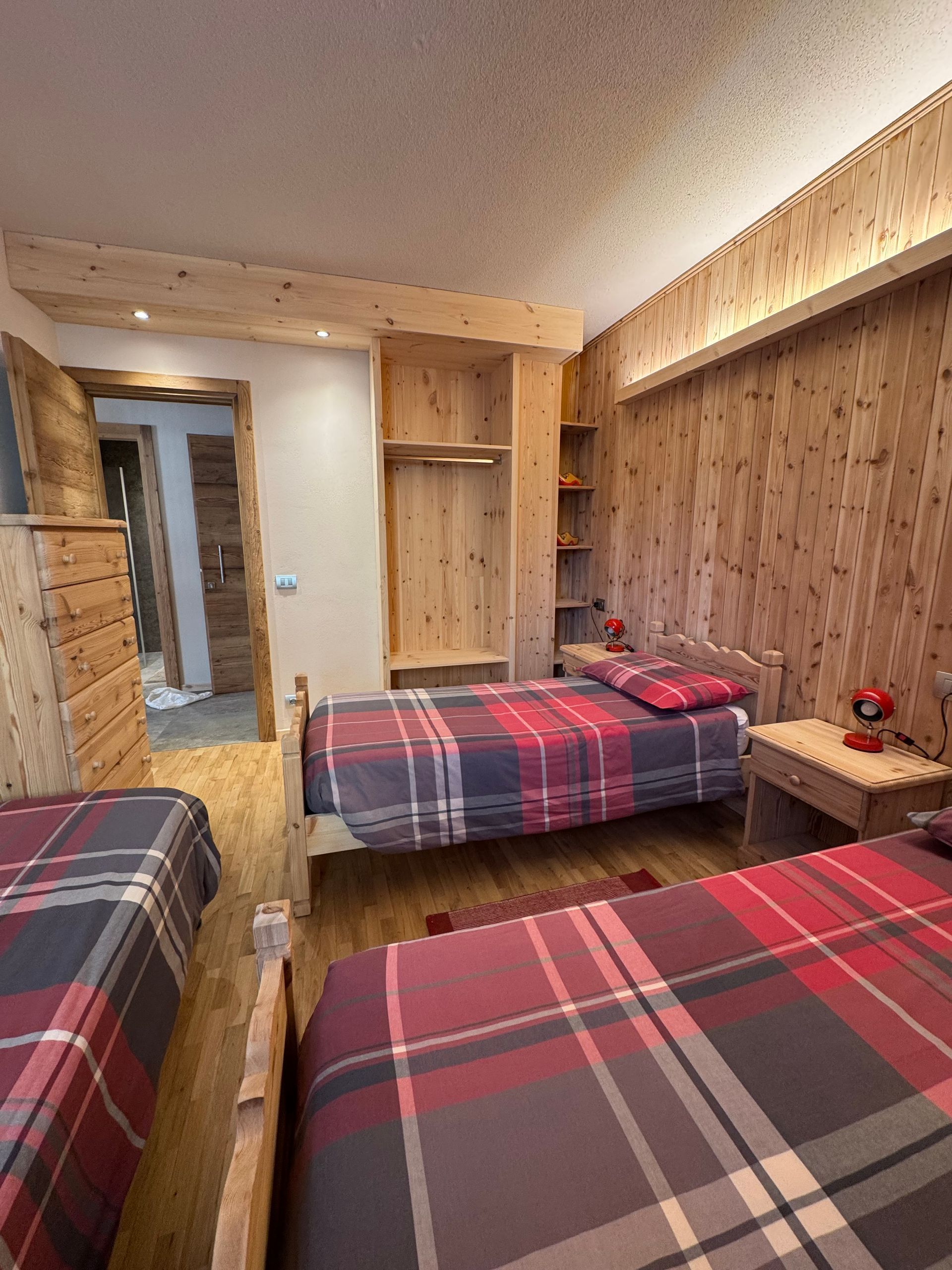 A bedroom with two beds and a wooden wall.
