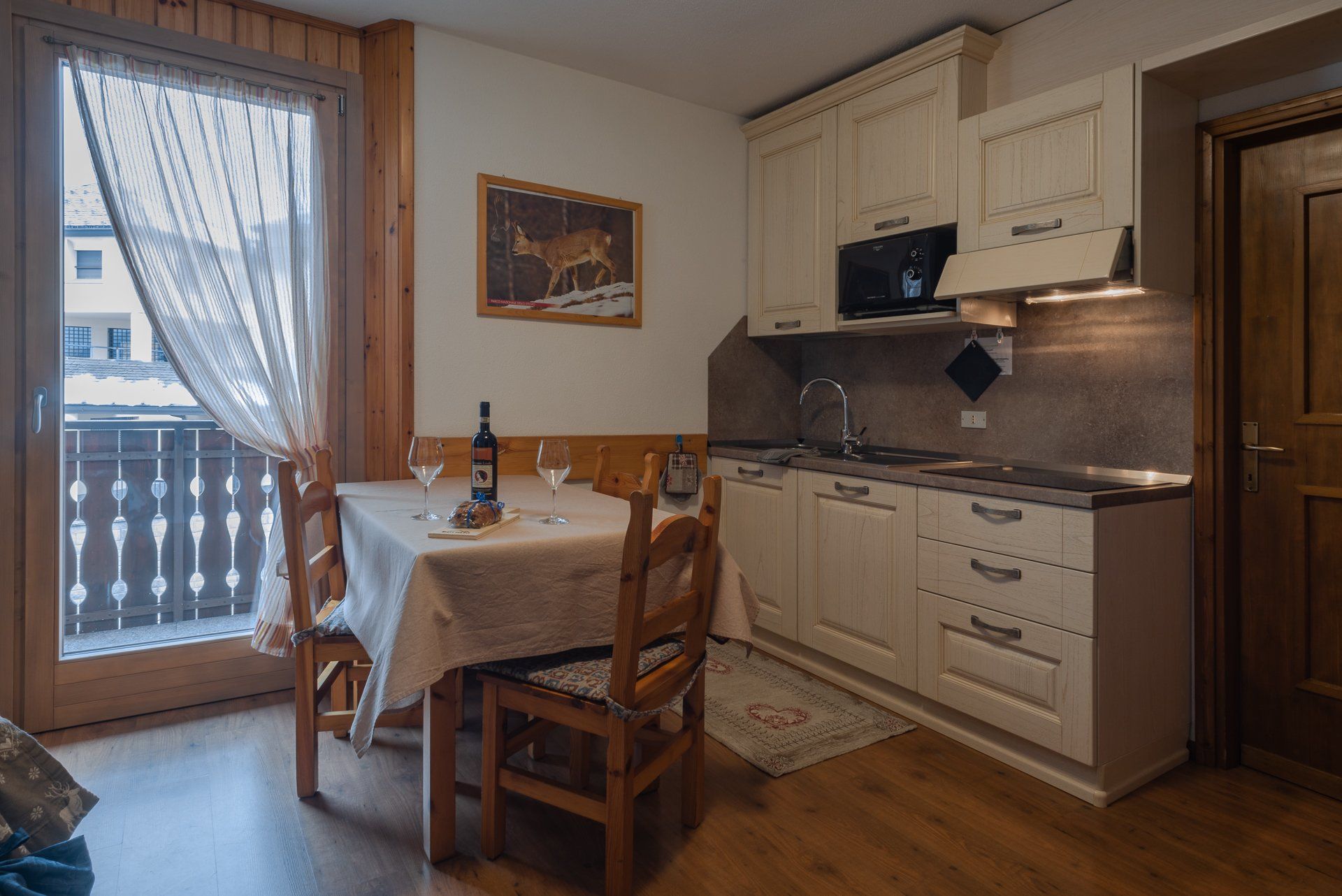 Una cucina con tavolo e sedie e una bottiglia di vino sul tavolo.