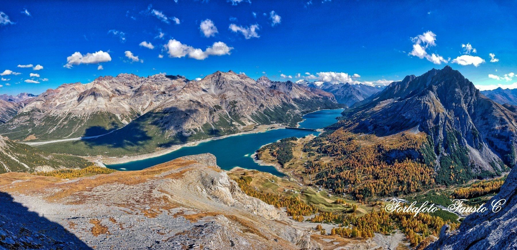 Una veduta aerea di un lago circondato da montagne in una giornata di sole.