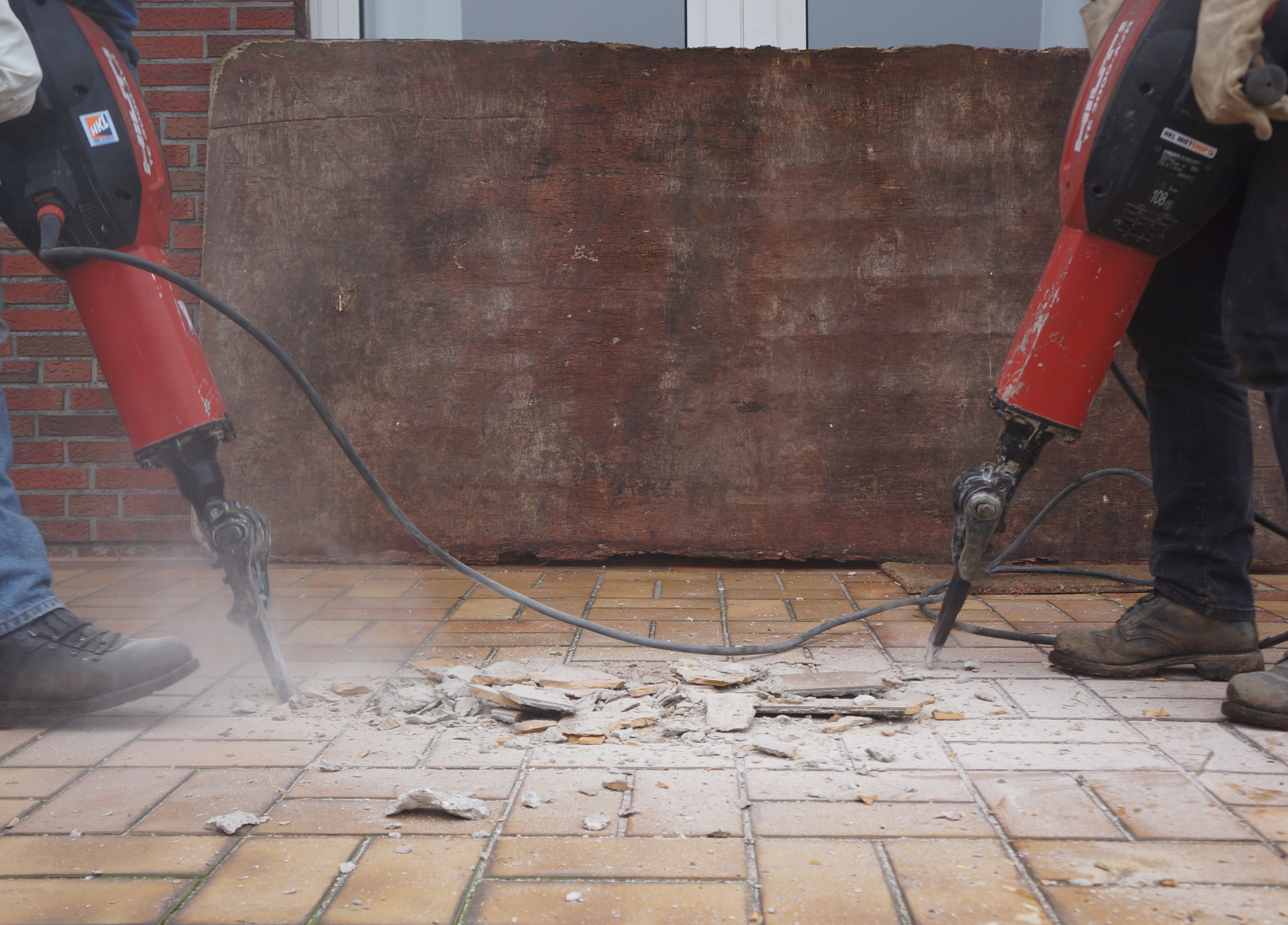 A person is using a hammer to break a brick wall.