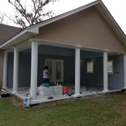 Person painting a house’s front porch with white trim and blue-gray walls