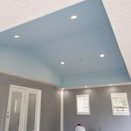 Modern room with blue vaulted ceiling, recessed lights, gray walls, and white French doors.