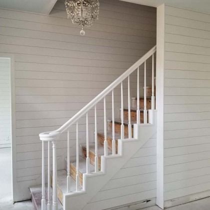 White staircase with wooden steps and railings in a light gray interior room