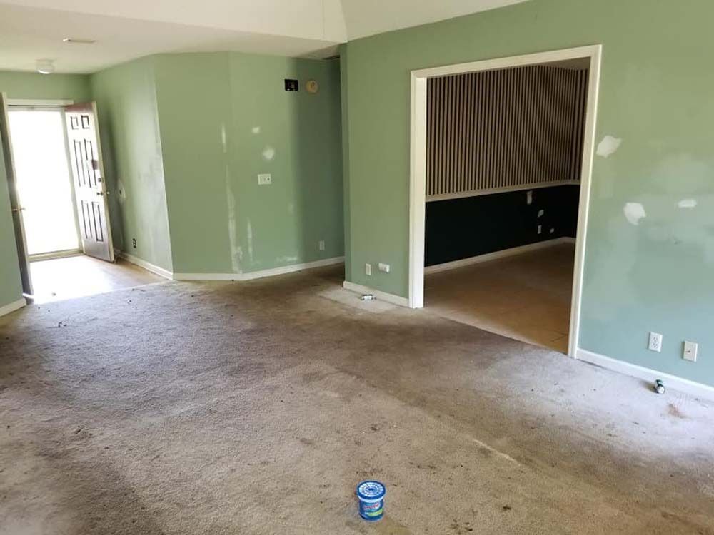 Empty living room with green walls, carpet, and a doorway to a curtained adjoining room