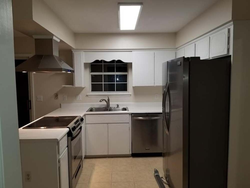 Modern kitchen with white cabinets, stainless steel appliances, and a sink under a window