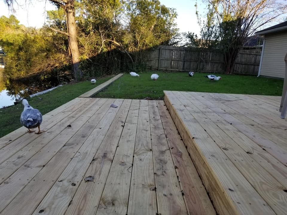 Wooden backyard deck leading to a grassy yard with several white birds near a fence.