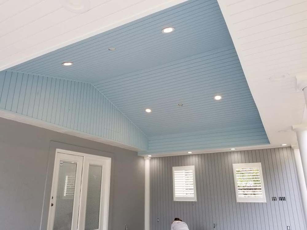 Modern interior room with blue slanted ceiling, gray walls, white trim, and recessed lights