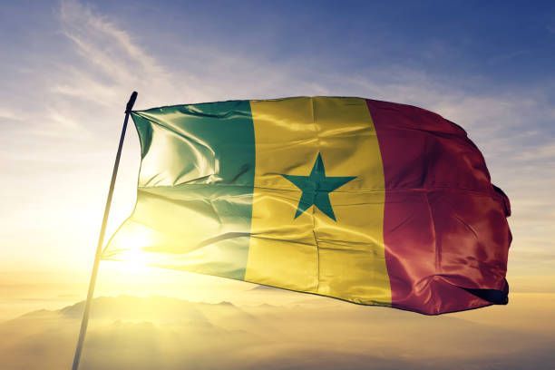Senegal flag waving in sunlight against a cloudy sky.