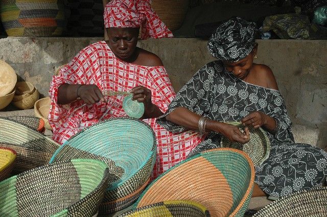 Two women weaving colorful baskets.