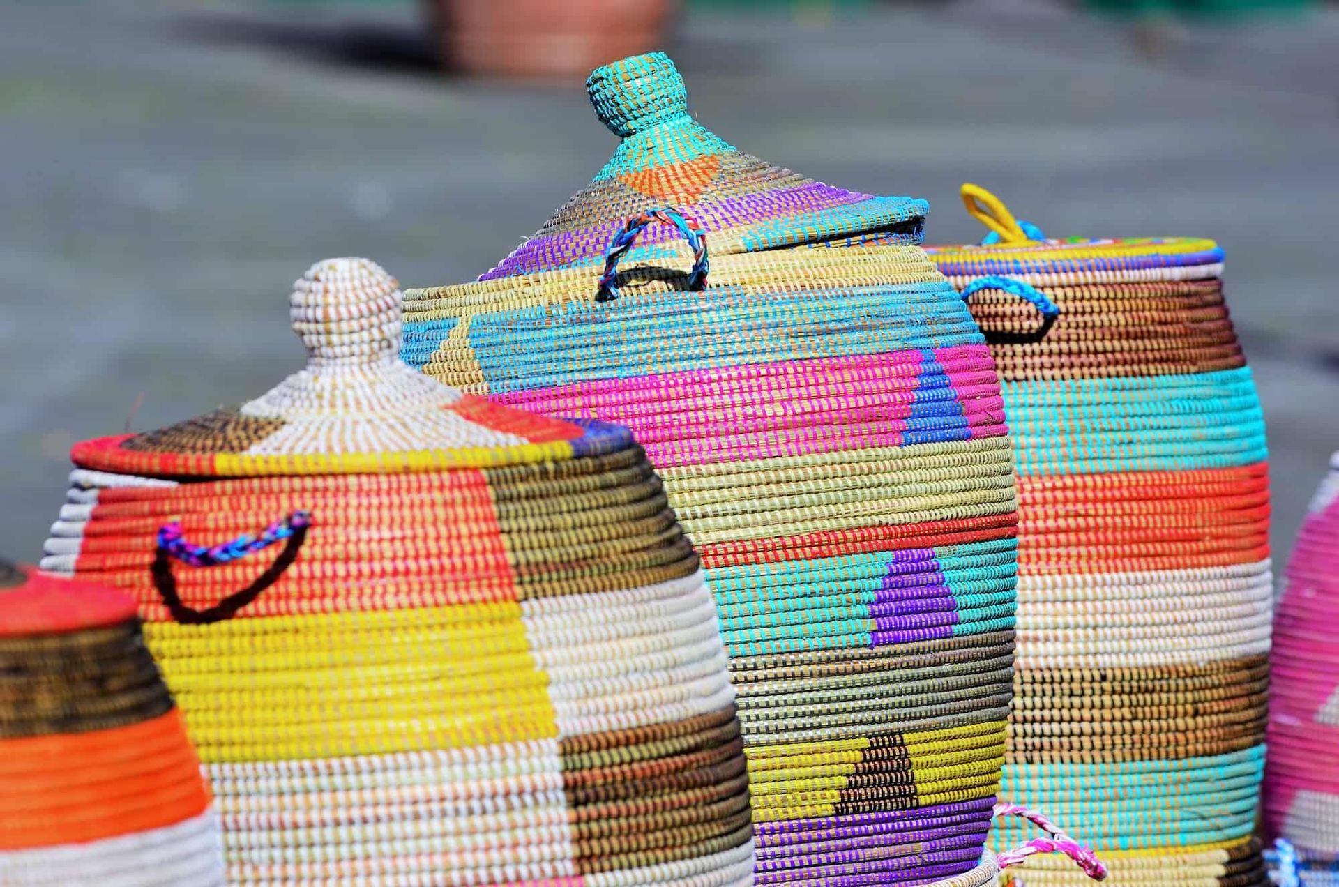 Colorful woven baskets with lids, arranged outdoors.