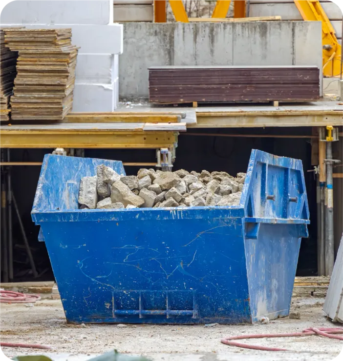 Blue construction dumpster filled with debris at a construction site.