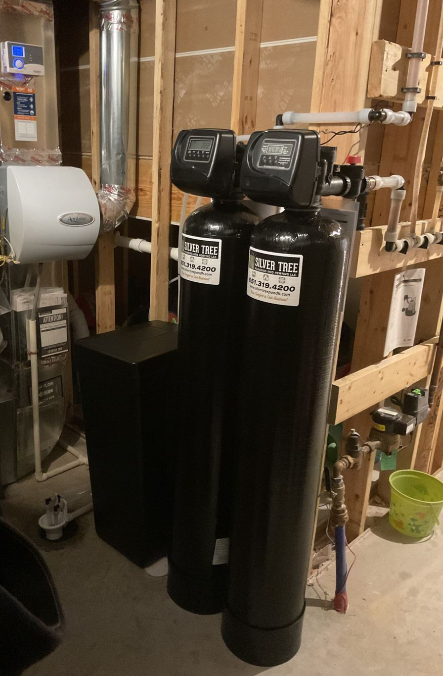 A water heater is sitting in a basement next to a wall.