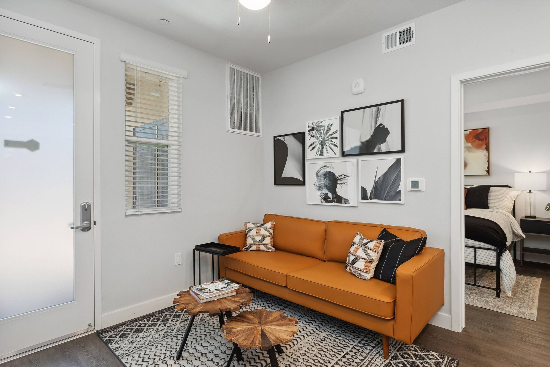 Modern living room with an orange sofa, wall art, and 2 coffee tables at Maven on Broadway.