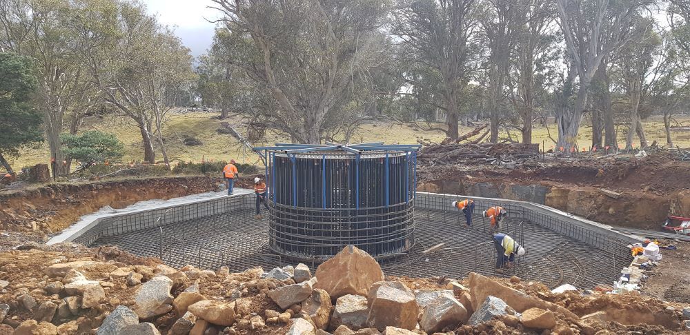 A group of construction workers are working on a large structure in the middle of a field.