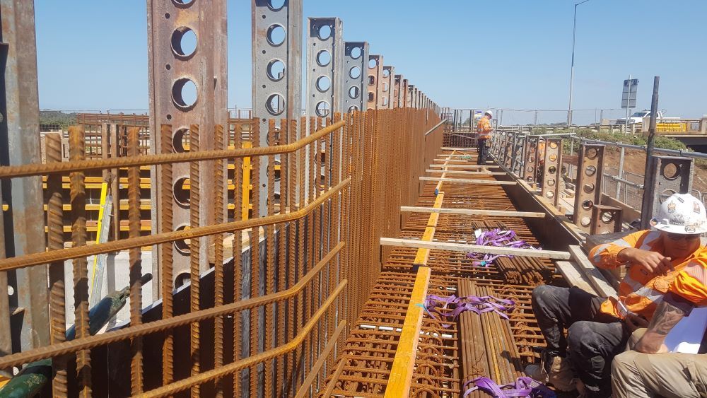 Western Steel Fixers' worksite with a white truck on-site near a bridge under construction.