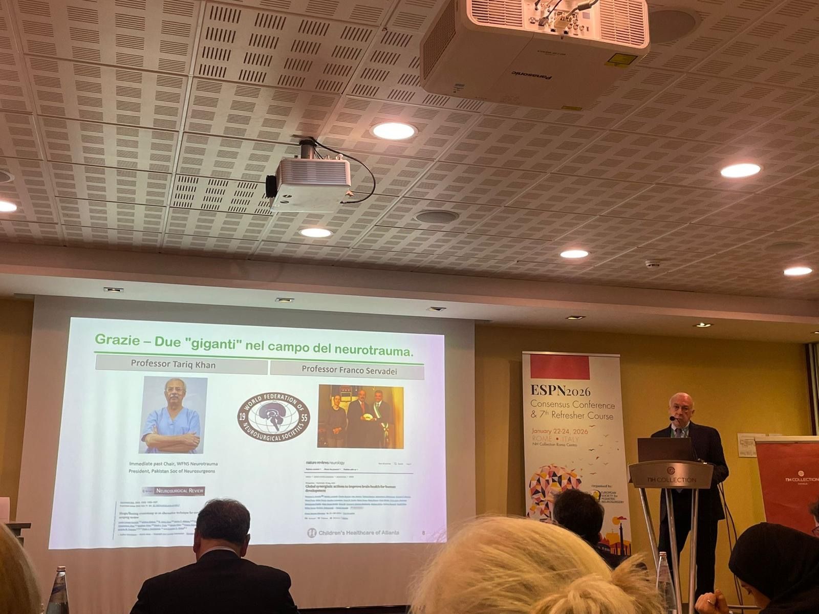 Dr. Reisner presenting at a conference, with a slide visible.