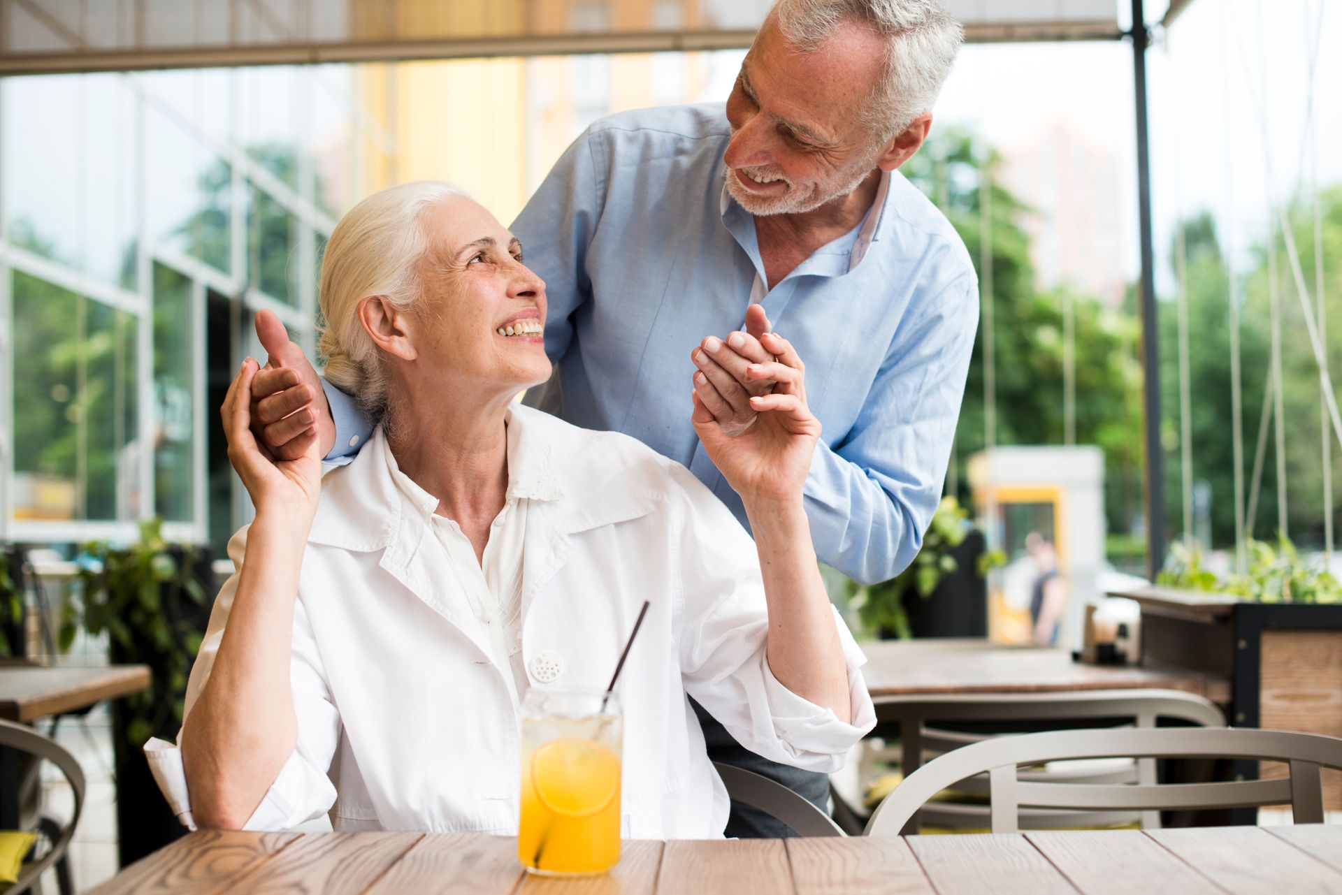 An elderly couple is dancing at a table in a restaurant.