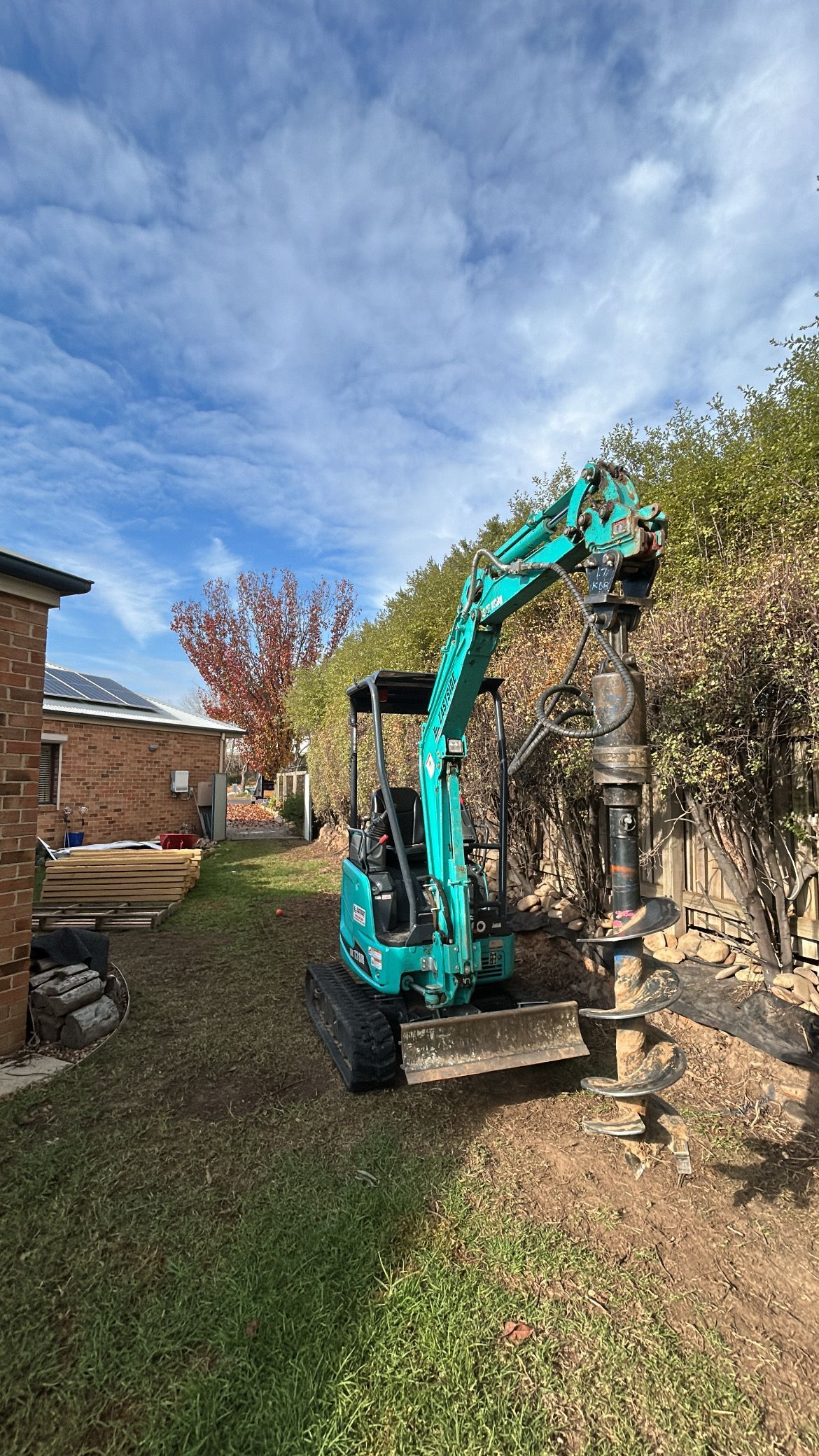 A small teal excavator drilling near a bush on a sunny day — The Wright Way Building In North Albury, NSW