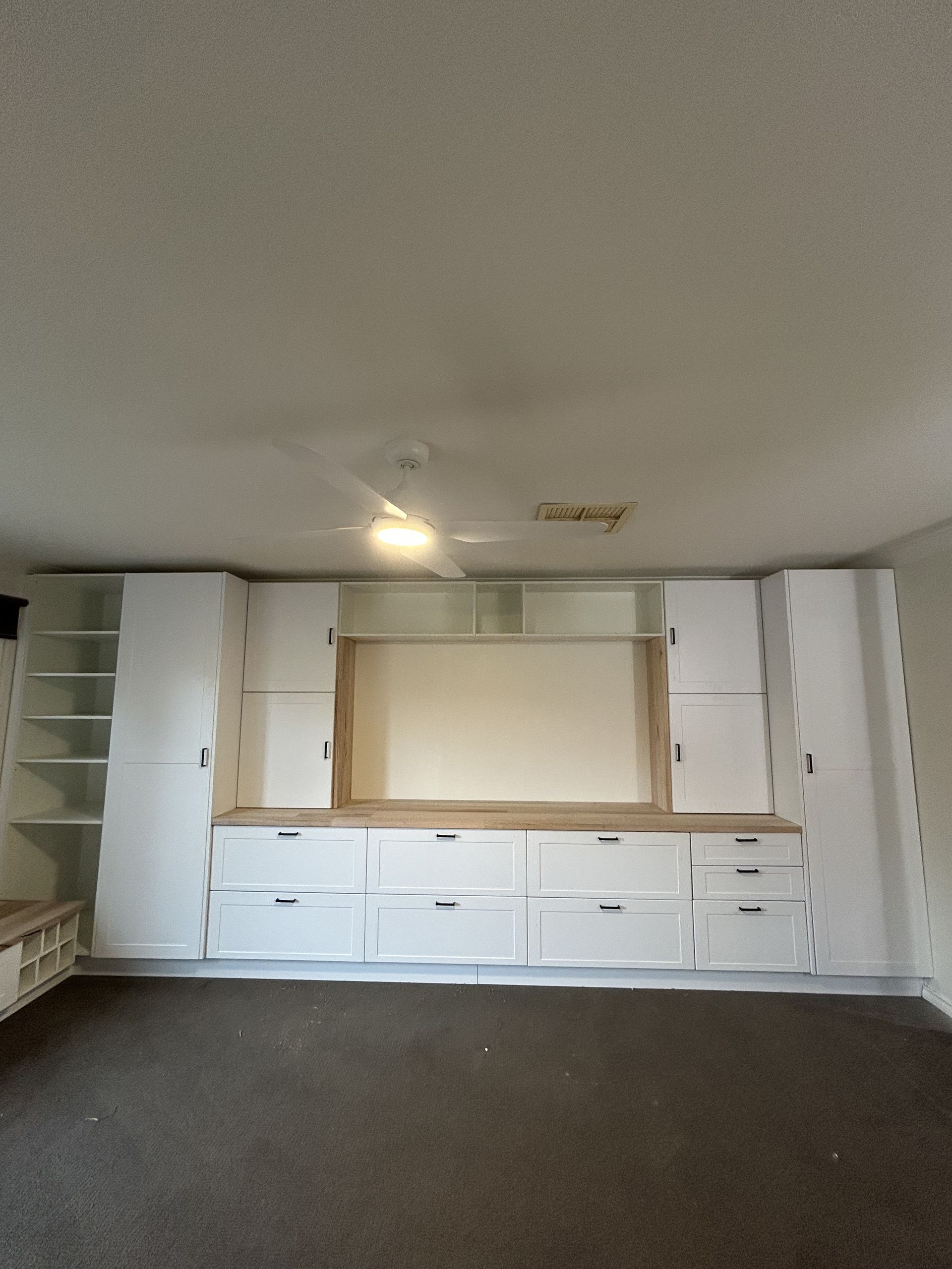 Built-in white storage cabinets and drawers span a wall, above a long countertop, with empty space in the center — The Wright Way Building In North Albury, NSW