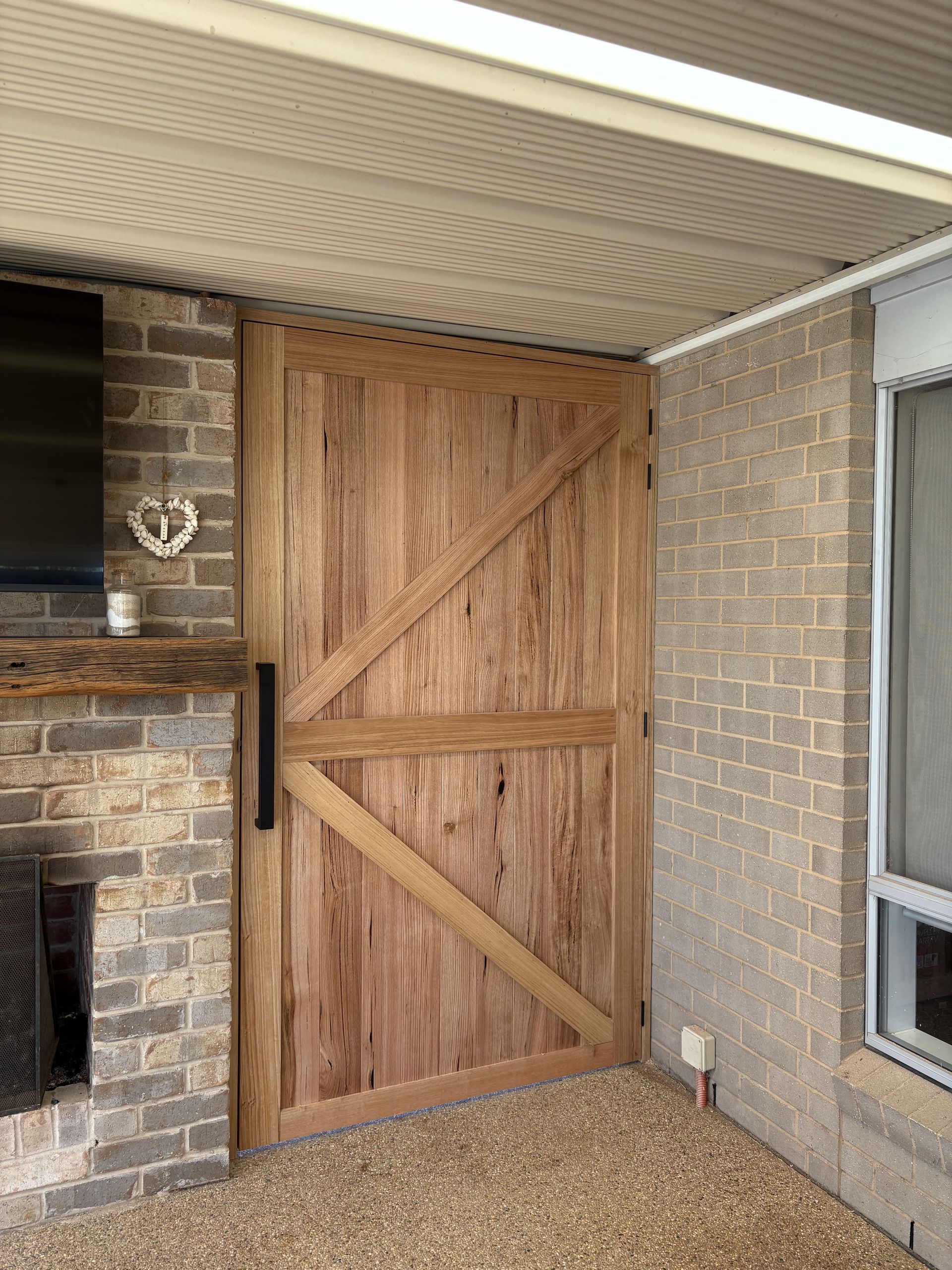 Wooden barn-style door on a brick patio, against a brick wall — The Wright Way Building In North Albury, NSW