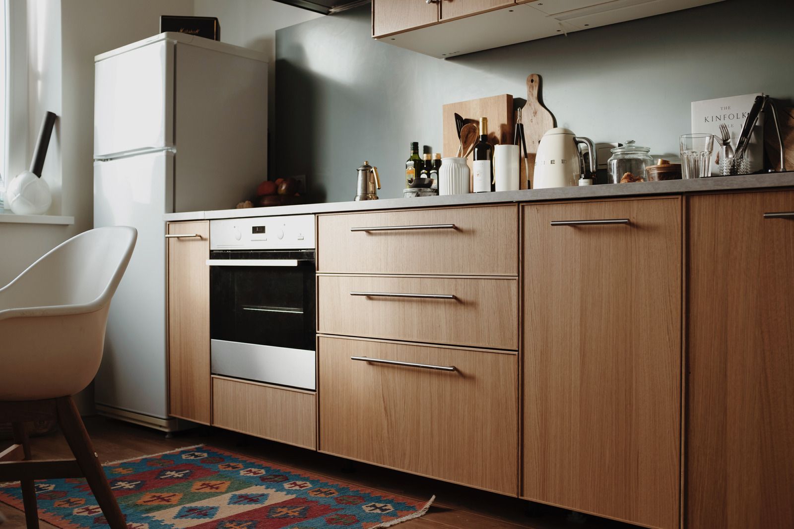 Modern kitchen with wooden cabinets, white appliances, and a patterned rug on the floor