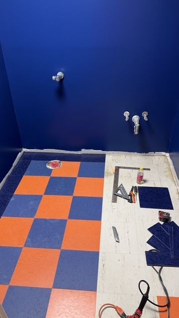 Small bathroom under renovation with blue and white walls, tiled floor, and tools scattered on the counter.