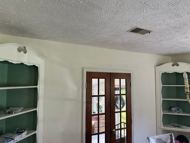 Living room with white built-in shelves and glass double doors leading outside