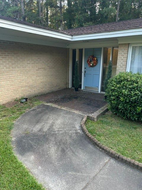 Front entry with curved concrete walkway leading to a blue door on a brick house